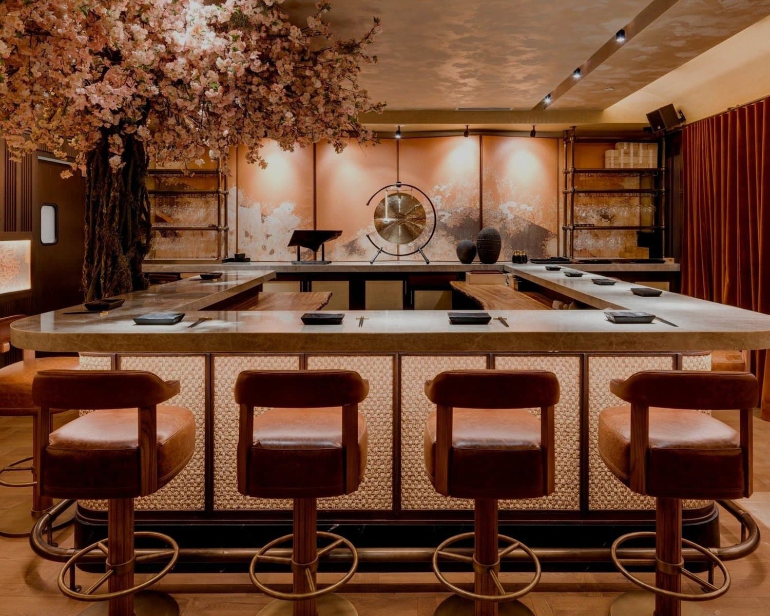 Modern omakase counter with wooden stools, artificial cherry blossoms, and minimalist décor