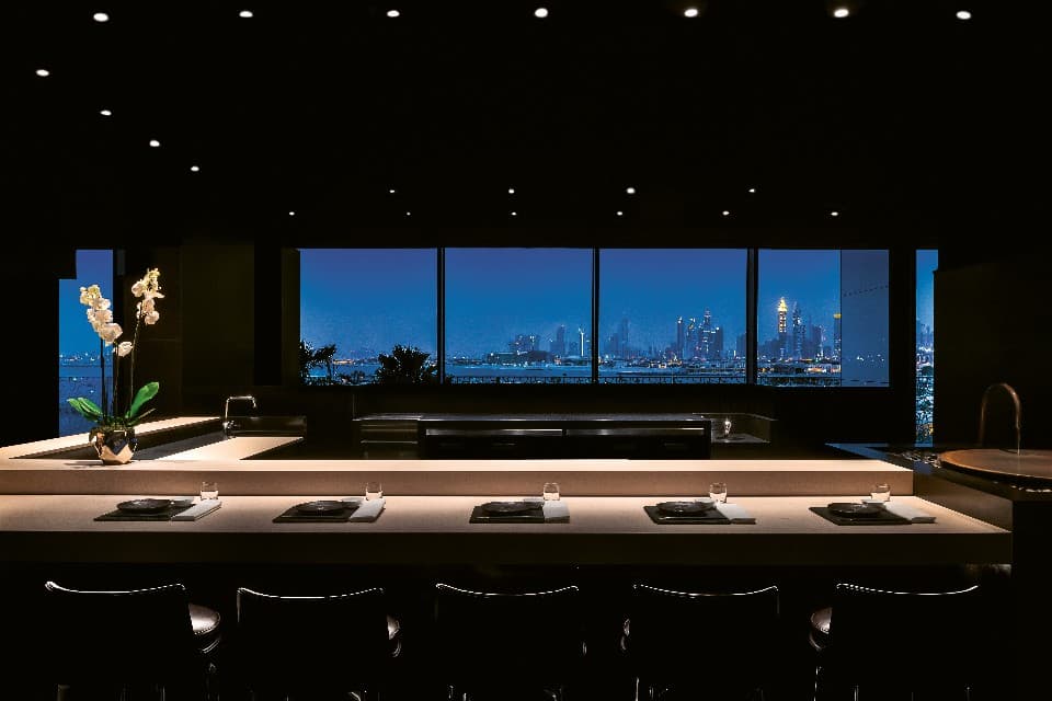 Modern sushi counter with city skyline view through floor-to-ceiling windows