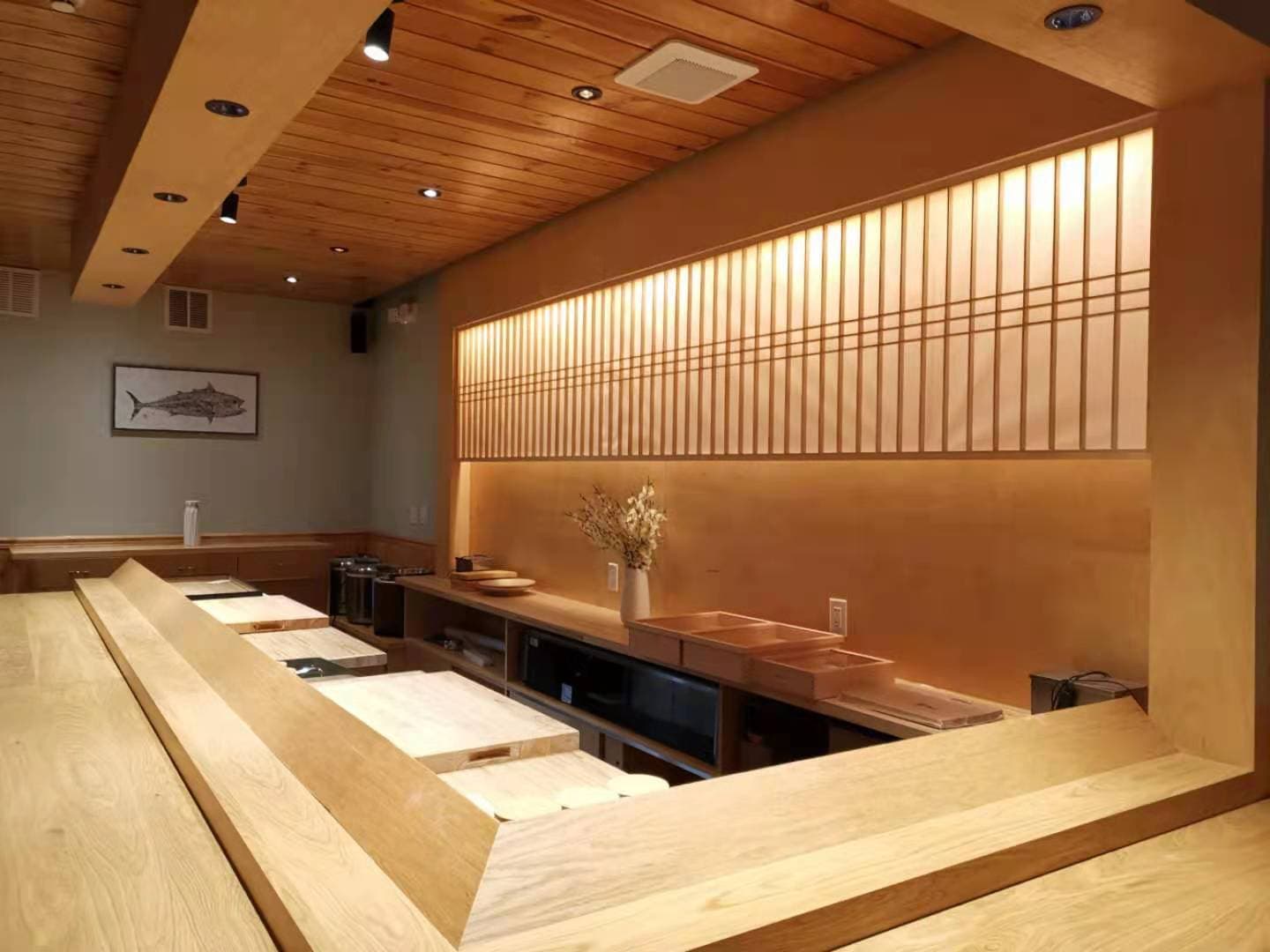 Modern sushi counter with light wood slatted wall and warm lighting