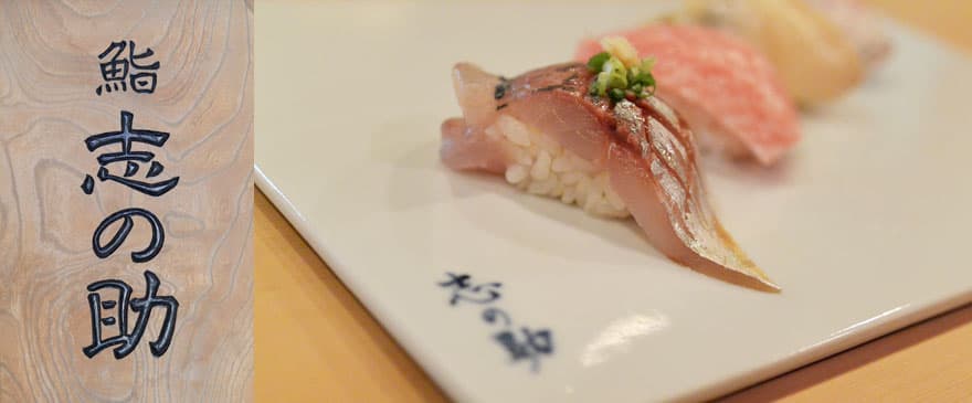 Nigiri sushi with fresh fish and garnish on a ceramic plate with Japanese text