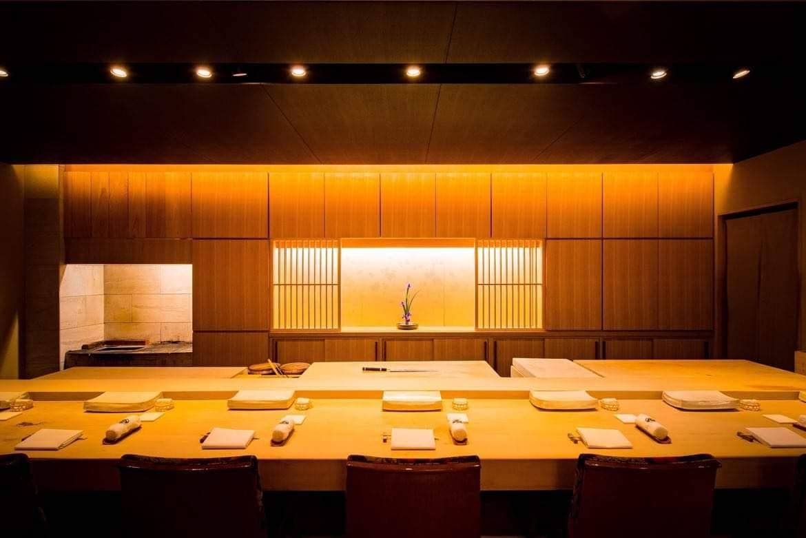 Modern sushi counter with wooden interior, ambient lighting, and pristine place settings
