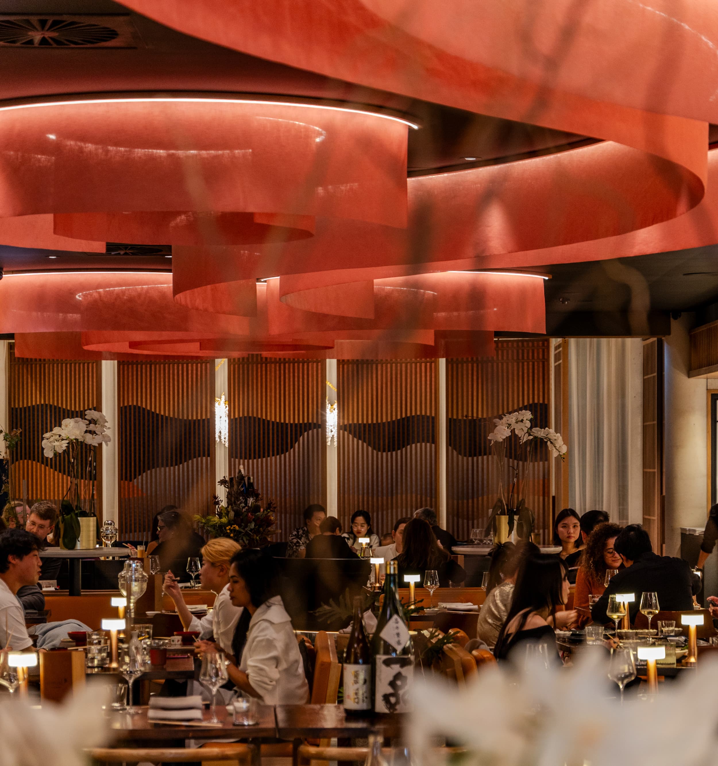 Elegant dining room with bold red sculptural ceiling and guests at tables