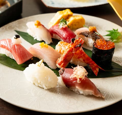 Assorted nigiri sushi platter with salmon, tuna, shrimp, and roe on white plate