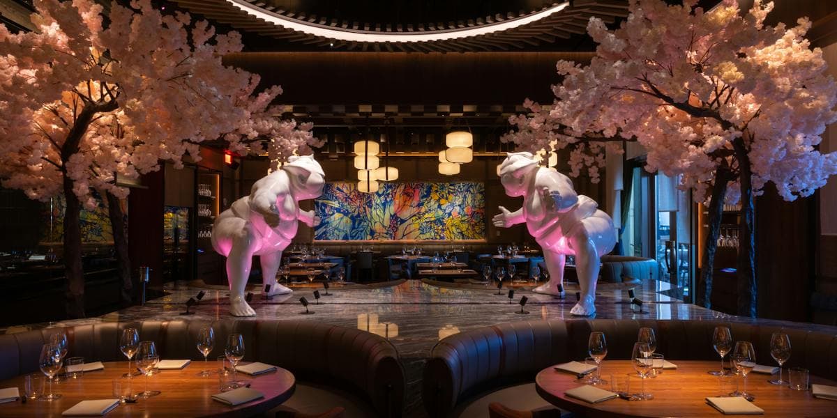 Elegant dining area with illuminated elephant sculptures, cherry blossom trees, and modern Asian-inspired decor