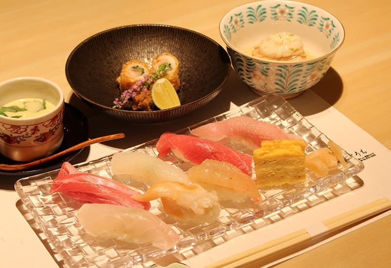 Sushi and sashimi platter with soup and cooked dish on wooden table