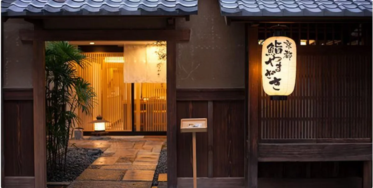 Traditional Japanese wooden storefront at night with illuminated lantern and tile roof