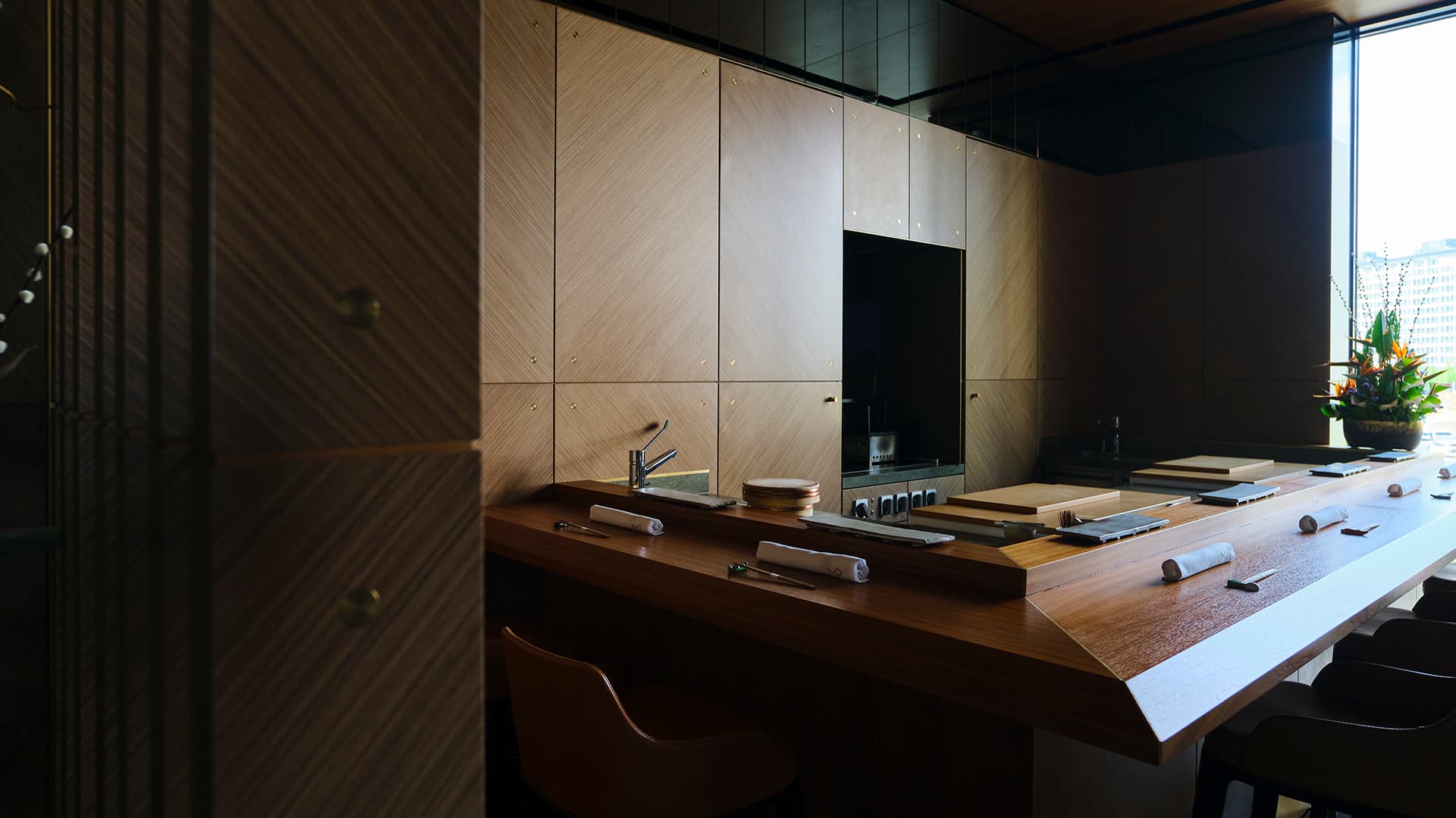 Modern omakase kitchen counter with wood and light-colored paneling, sushi preparation workspace