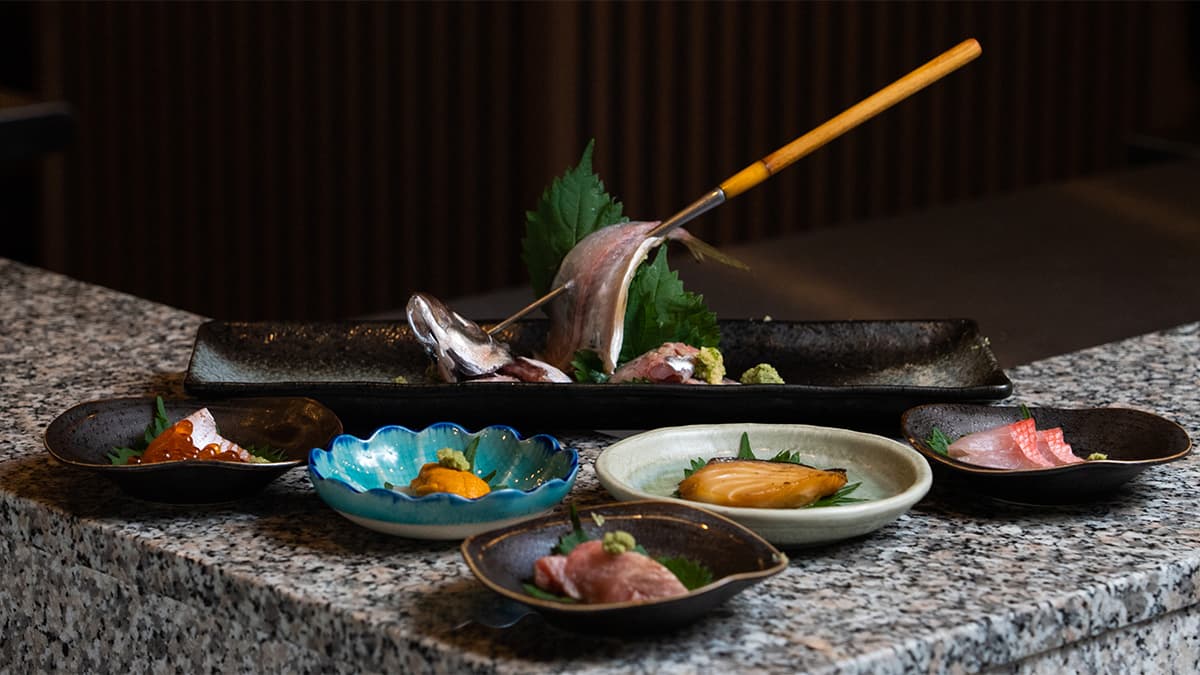 Artfully plated sushi and sashimi courses with decorative brush on stone surface