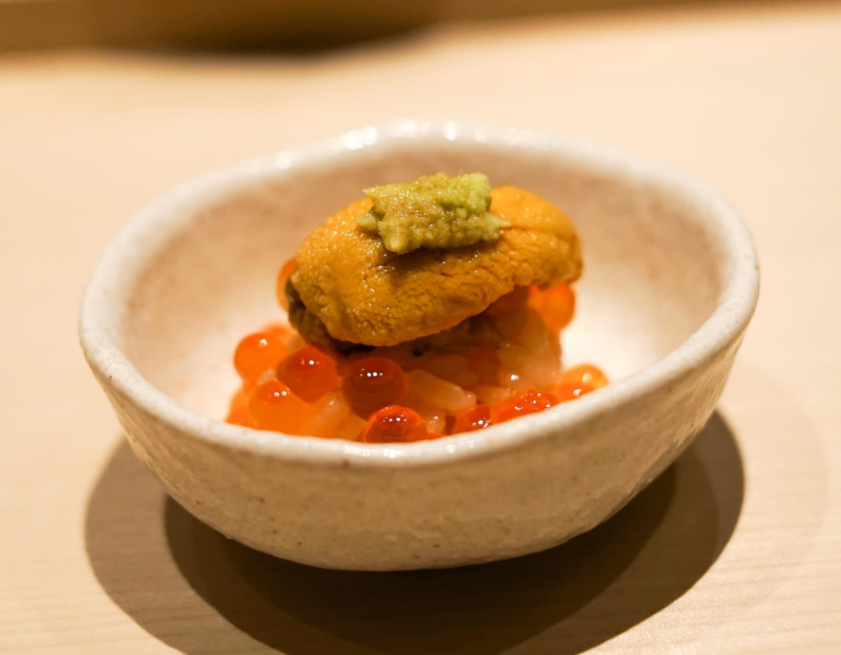 Fine dining plated dish with sea urchin and roe in white ceramic bowl