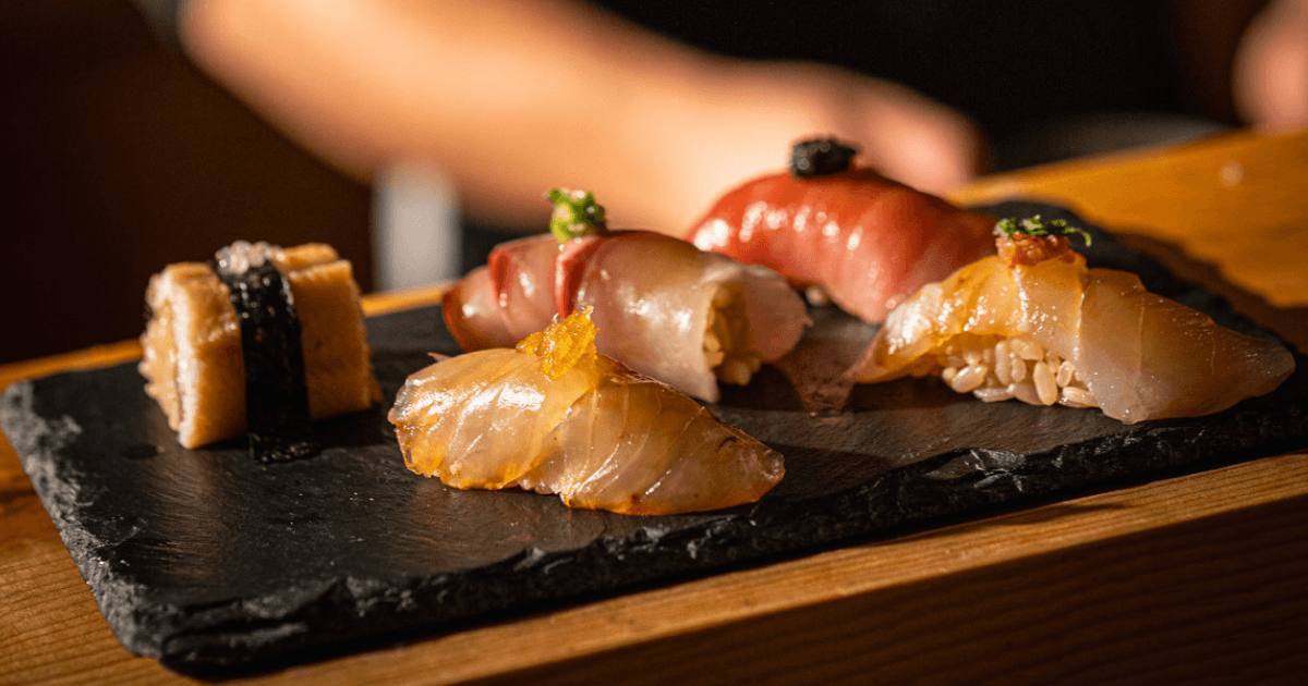 Assorted nigiri sushi on black slate with garnish