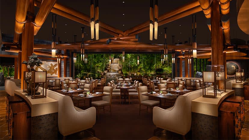 Modern restaurant dining room with wooden beams, warm lighting, and floor-to-ceiling windows overlooking greenery