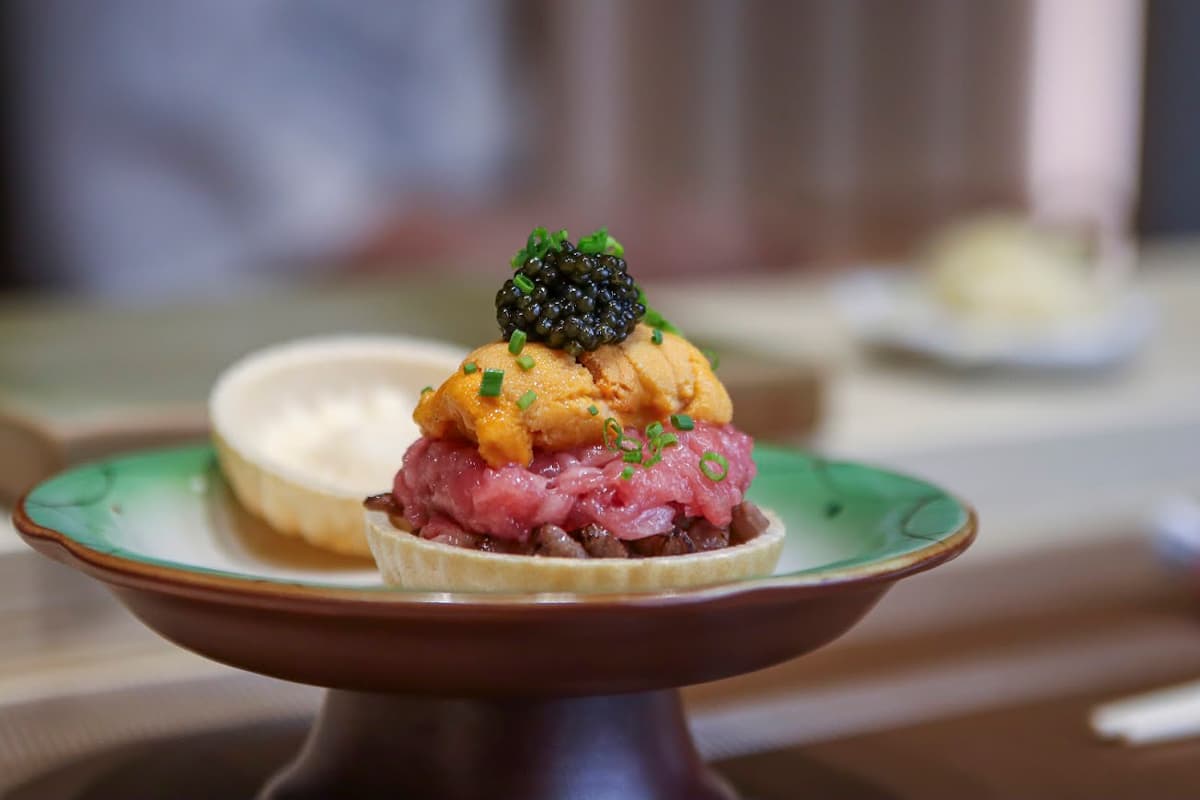Plated sashimi tower with caviar on a green ceramic dish