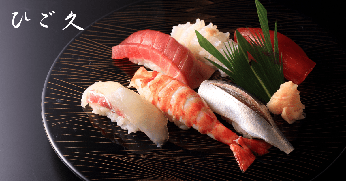 Assorted nigiri sushi on a black dish with gold accents