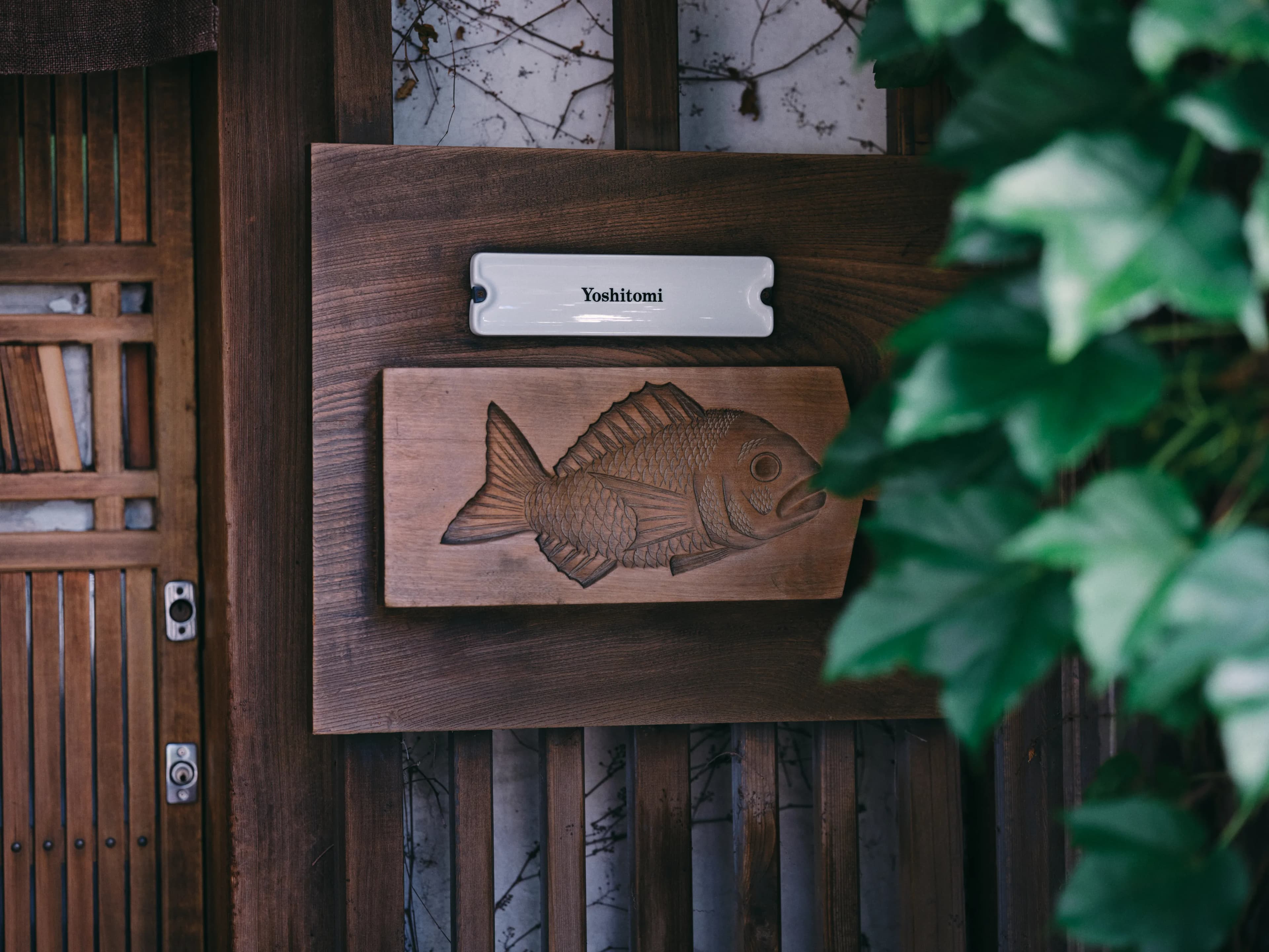 Wooden entrance gate with carved fish sign reading Yoshitomi