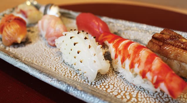 Elegantly plated sushi selection with various nigiri and rolls on a textured ceramic plate