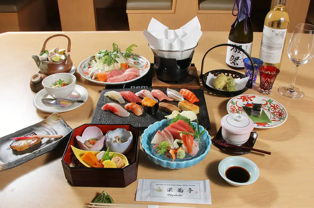 Elegant Japanese kaiseki dinner spread with sushi, sashimi, broth, and sake on wooden table