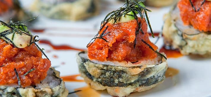Plated appetizer with orange roe and seaweed garnish on white plate