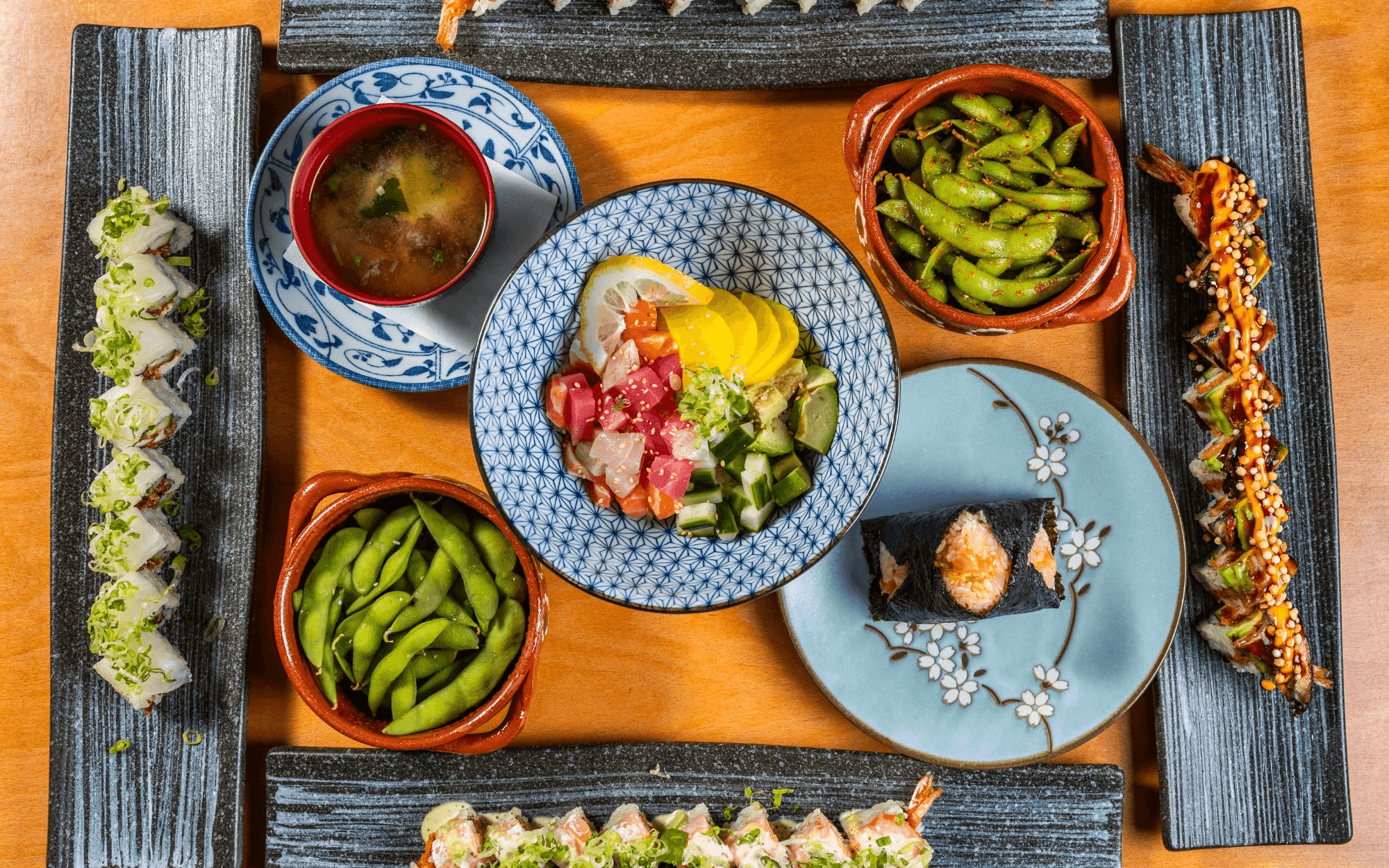 Plated Asian cuisine with sushi rolls, soup, sashimi, and edamame appetizers