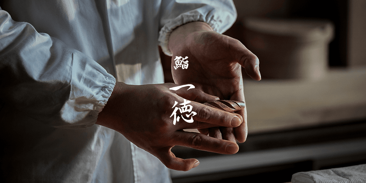 Hands holding a small object with Japanese characters overlaid